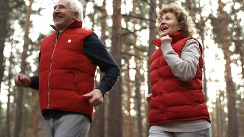 Senior Couple Jogging Together Through a Forest