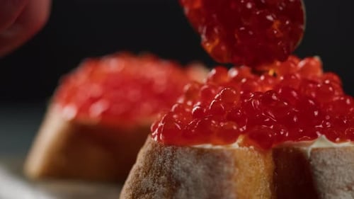 Pouring Red Caviar on Bread with Cream Cheese