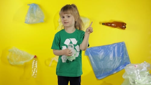 Niña activista voluntaria con camiseta verde con Logo de reciclaje. Contaminación plástica