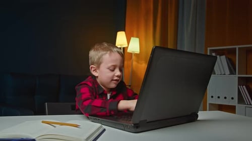 Boy Using Laptop Computer At Home At Night