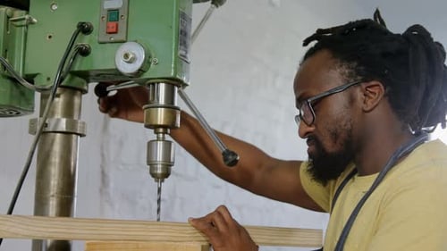 Carpenter drilling wooden plank with machine in workshop 4k