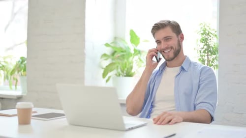 Young Man Talking on Phone at Desk