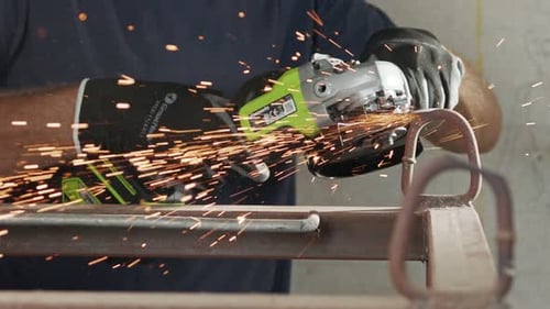 Man Grinding Metal with Power Tool in Workshop