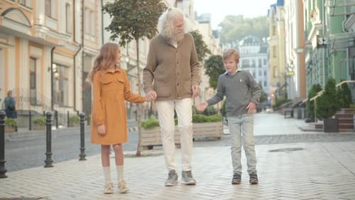 Grandfather Walking with Grandchildren in City Street