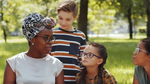 Children Listening to Afro-American Female Teacher on Lesson in Park