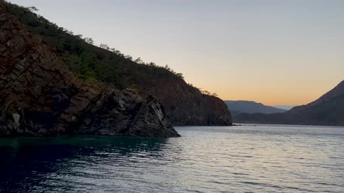 Colorful sunset by the sea with waves on the surface of the water and the silhouettes of a cartel an