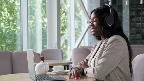 Cheerful Black Woman with Headphones Talks on Videocall