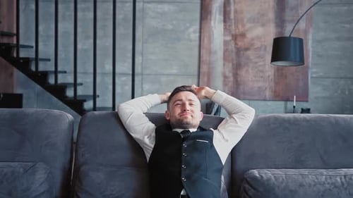 Handsome Man European Appearance Classic Clothes White Shirt Sits in Stylish Dark Office on Couch
