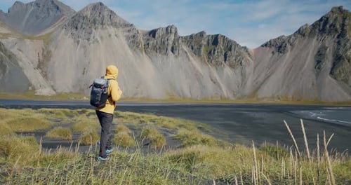 Male Traveler Looking to Fantastic Mountains on Volcanic Lava Sand Dunes on the Beach Stokksness