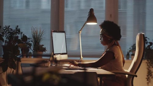 Femme d'affaires noire travaillant sur un ordinateur le soir