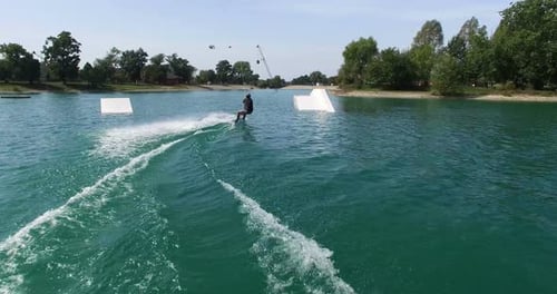 Rückansicht eines Mannes springt im Wakepark über den Kicker