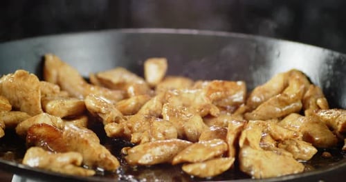 Chicken Pieces Sizzling in a Frying Pan