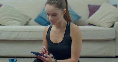 Woman Using Smartphone After Workout at Home