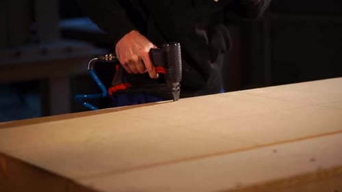 Man Using a Staple Gun on Wood