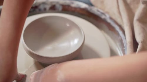 Potter découpe un bol en céramique dans une roue de potier, vue rapprochée
