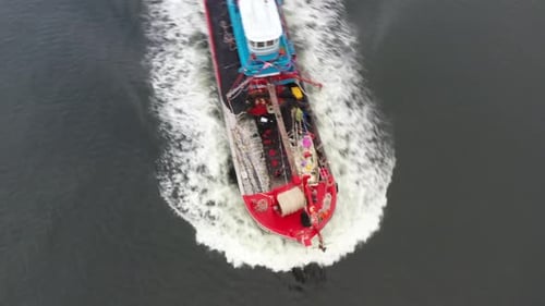 Birds eye view drone fly around a traditional fishing boat with foamy wake, sailing on the sea, fish