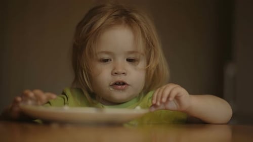Child Eats Food with Hands at Table