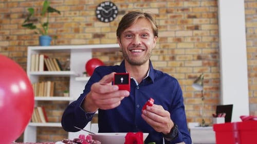 Portrait of caucasian man showing a ring on videocall at home