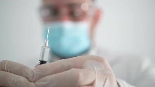 Medical Professional Prepares Syringe and Needle For Shot