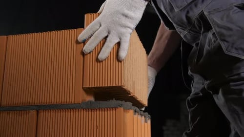 Man laying brick block on cement