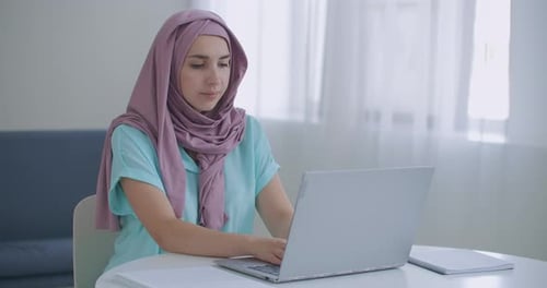 Woman Types on Laptop at Table Indoors