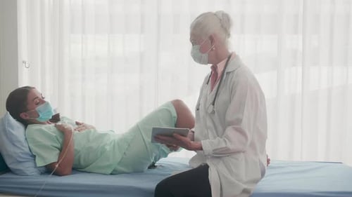 Patient talking with doctor senior feeling worried about disease and lying down at hospital.