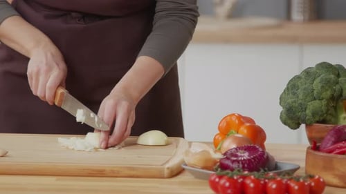 Woman Chopping Onion at Kitchen Table