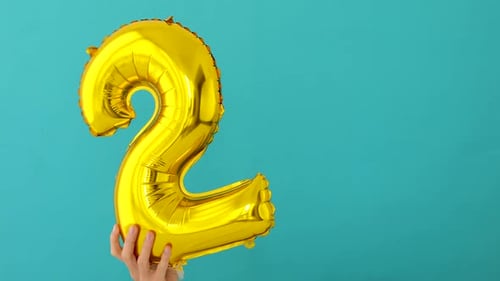 Shiny Metallic Number Two Balloon Held by Hand