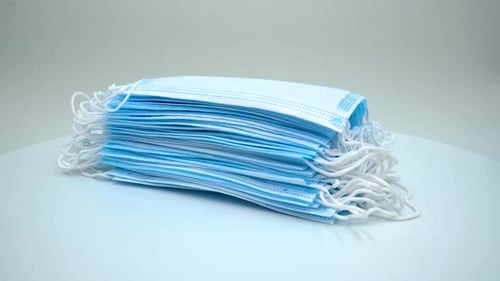 Stack of blue surgical masks on white surface