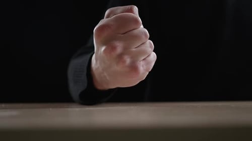 Clenched Fist on Table in Dark Room