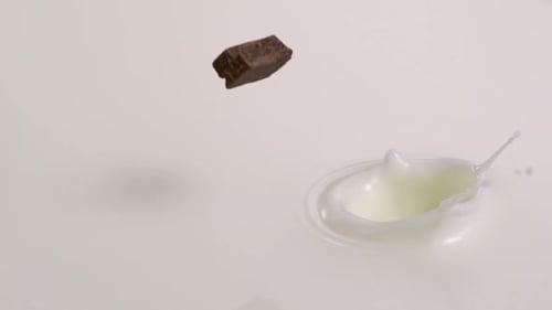 Chocolate Pieces Splashing into a Pool of Milk
