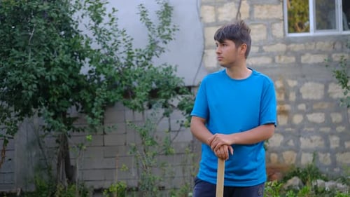 Young Adult with Tool Standing in Yard