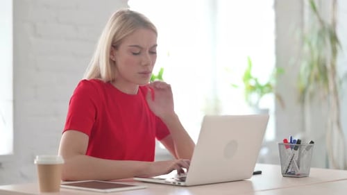 Young Blonde Woman having Neck Pain while using Laptop in Office