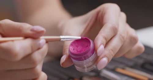 Professioneller Visagist, der flüssigen rosa Lippenstift auf die Handhaut aufträgt, Nahaufnahme