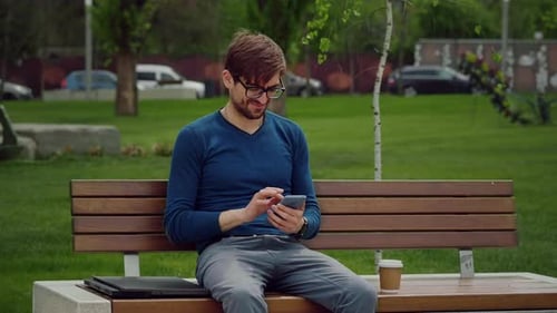 Portrait focused man writing using mobile phone outdoor.