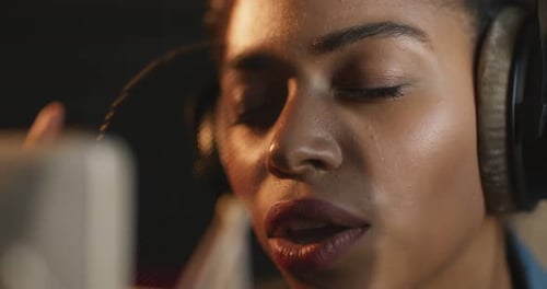 Close Up of African American Singer Recording Song with Headphones and Professional Microphone