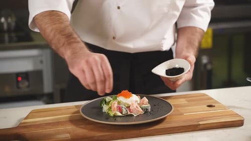Chef Garnishing Fresh Salmon Salad with Seeds