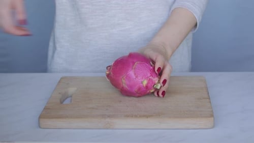Woman Cuts Dragon Fruit in Half With Knife
