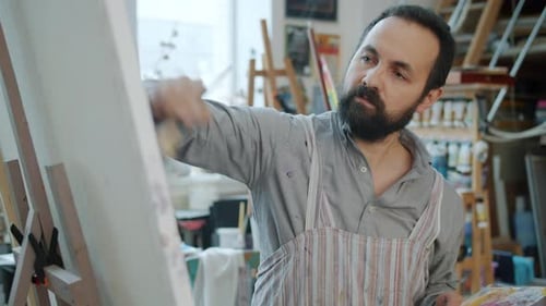 Slow Motion of Attractive Bearded Man Painter Working at Picture Painting Indoors in Studio