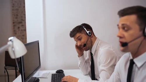Two Technical Support Specialist Talking with Customers By Headsets.