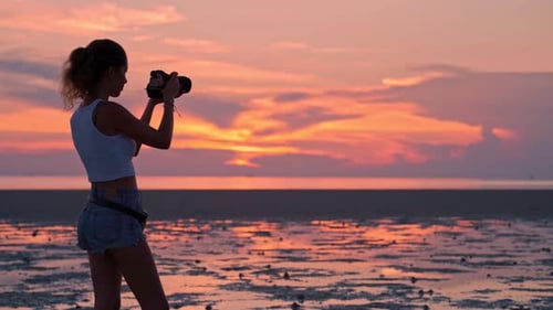 Femme prenant des photos du coucher de soleil sur la plage