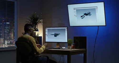 Junger Mann lehnt sich zurück und bearbeitet ein 3D-Modell auf seinem Computer
