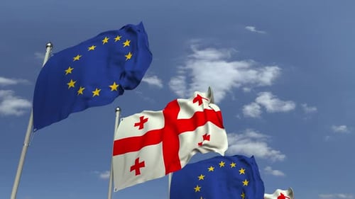 Realistic Flags of Georgia and European Union Waving in Blue Sky