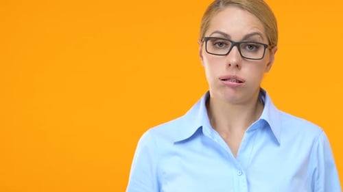 Annoyed Woman Dismissively Waves Hand on Orange Background