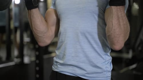 Close up image of man using barbell at the gym.