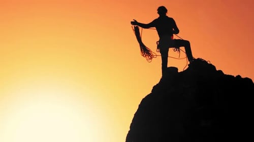 A Climber At The Top Of The Rock Throws The Rope Down