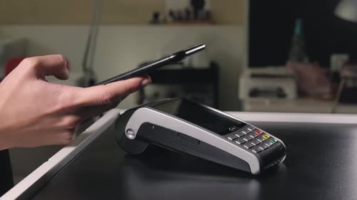 Woman Paying with NFC Technology with Smart Phone Credit Card Application in Clothing Store Beauty