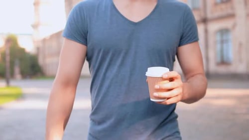 Man Walks and Drinks Coffee Outdoors