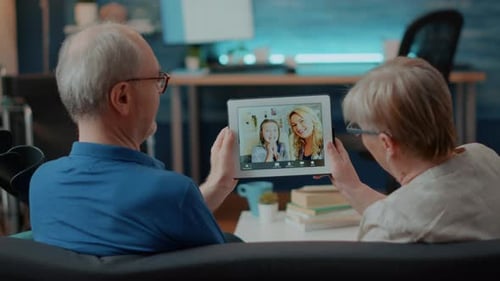Senior Couple Video Calling Family on Tablet Indoors