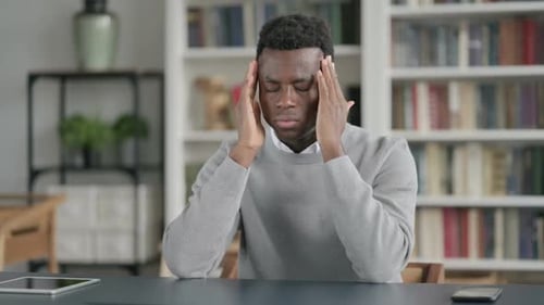 African Man Having Headache While Sitting in Library